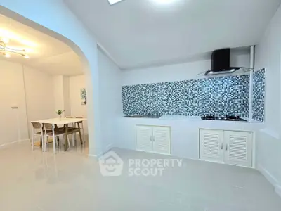 Modern kitchen with mosaic backsplash and dining area in open layout