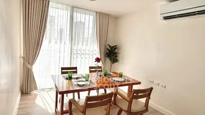 Bright dining area with modern table set and large window in stylish apartment.