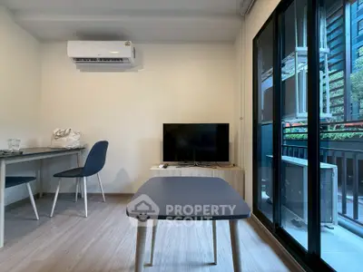 Modern living room with sleek furniture and balcony view, featuring air conditioning and natural light.