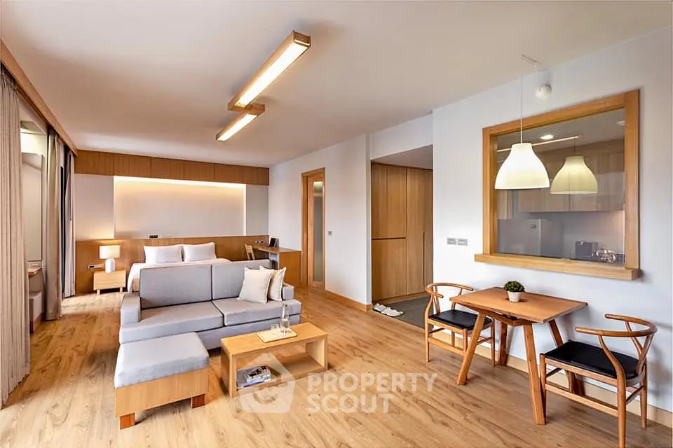Modern open-plan living room with cozy seating and dining area, featuring wooden flooring and stylish lighting.