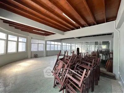 Spacious interior with wooden ceiling and stacked chairs, ideal for versatile use.