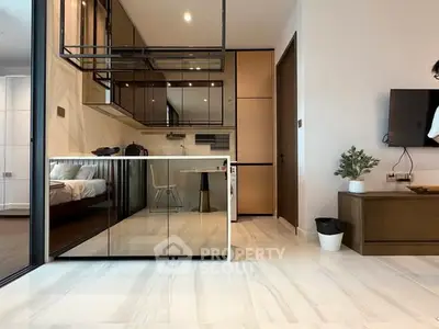 Modern open-plan living space with sleek kitchen and cozy bedroom view.