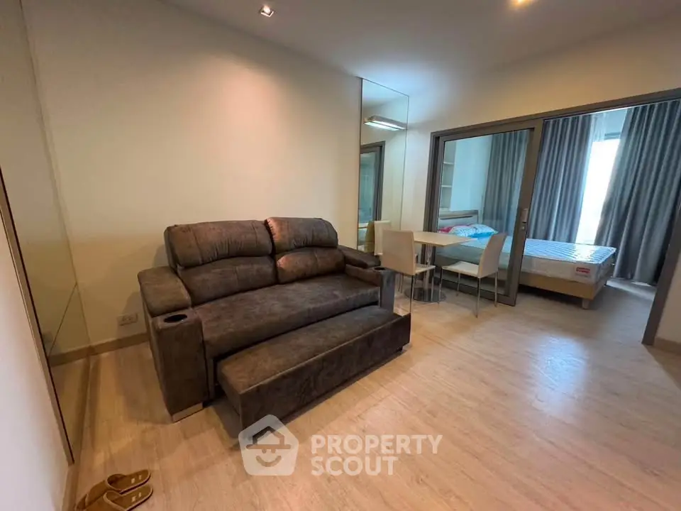 Modern living room with cozy sofa and view into bedroom, featuring stylish decor and open layout.