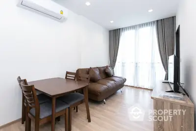 Modern living room with brown leather sofa and dining set, bright natural light from large window.