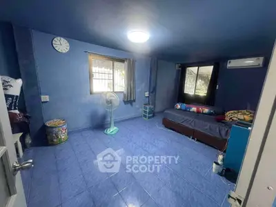 Spacious blue-themed room with air conditioning and natural light, ideal for comfortable living.