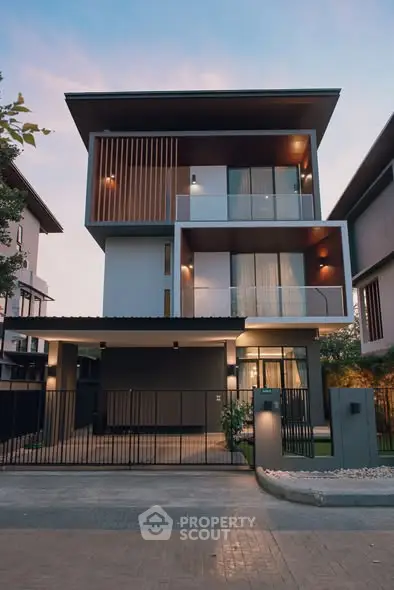 Modern three-story house with sleek design and large windows at dusk.