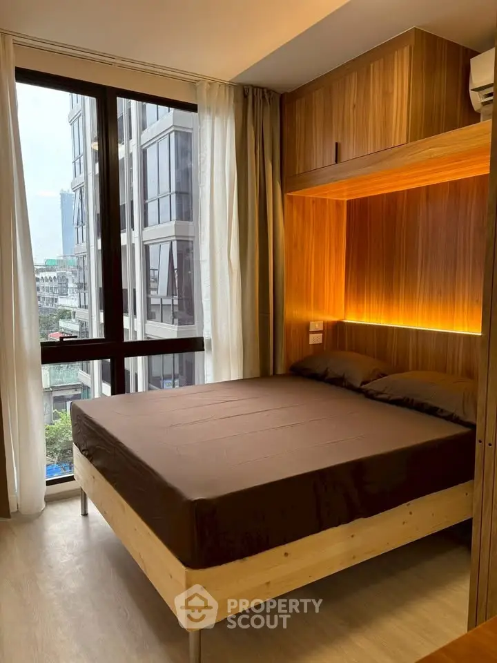 Modern bedroom with large window and wooden accents in urban apartment