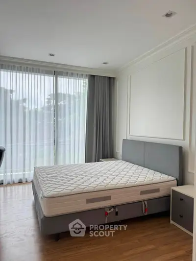 Spacious bedroom with large windows and modern decor, perfect for natural light lovers.