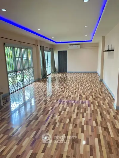Spacious living room with modern lighting and polished wooden flooring