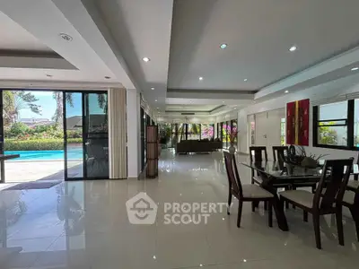 Spacious open-plan living and dining area with pool view, perfect for entertaining and relaxation.