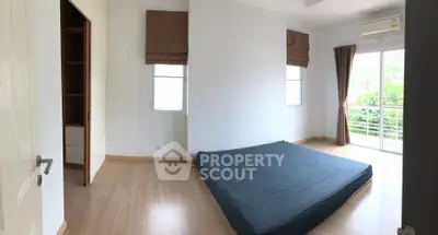 Spacious bedroom with large windows and balcony access, featuring minimalist design and natural light.