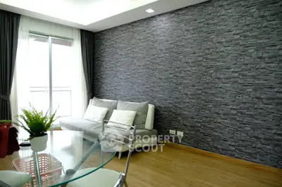 Modern living room with stone accent wall and glass table, featuring cozy sofa and natural light.