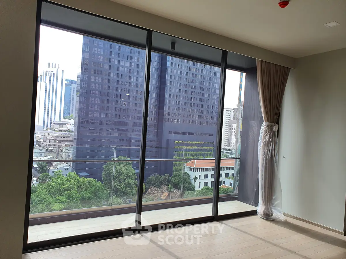 Spacious apartment with floor-to-ceiling windows offering stunning city views and a large balcony.