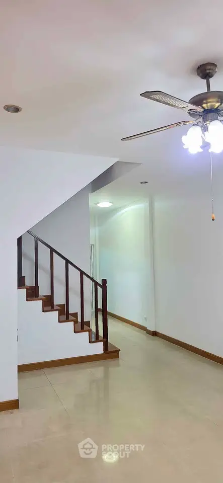 Spacious interior with modern staircase and ceiling fan, perfect for stylish living.