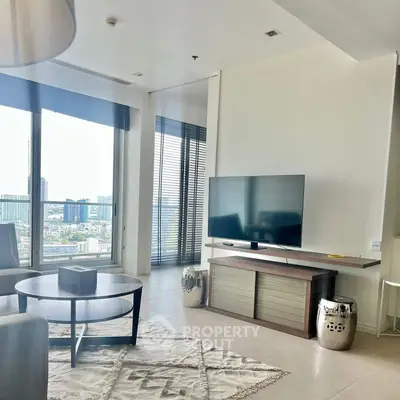 Modern living room with large windows and city view, featuring sleek furniture and a mounted TV.