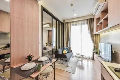 Modern open-plan living room with dining area and balcony access, featuring stylish decor and natural light.