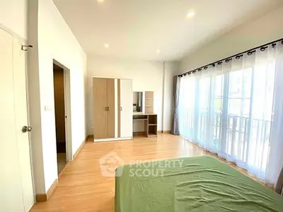 Spacious bedroom with large windows and modern furnishings in a bright apartment.