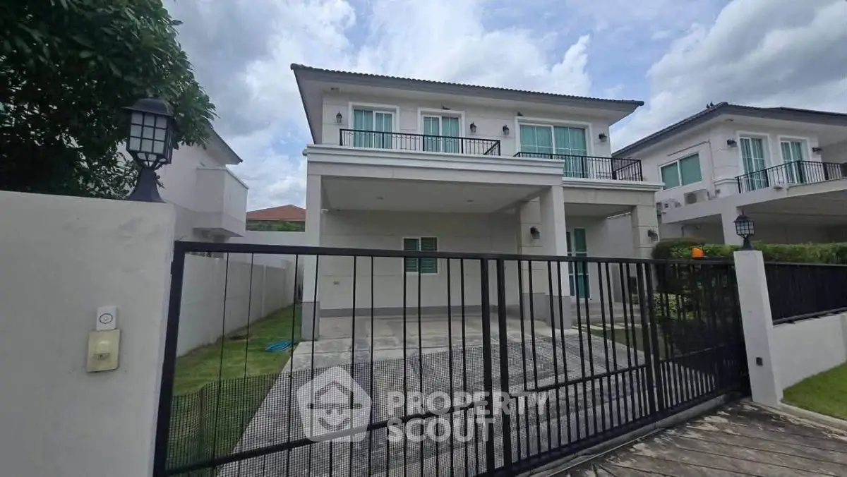 Modern two-story house with gated driveway and balcony, ideal for family living.