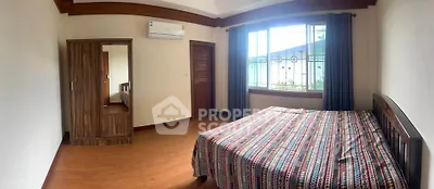 Spacious bedroom with wooden flooring and large window for natural light