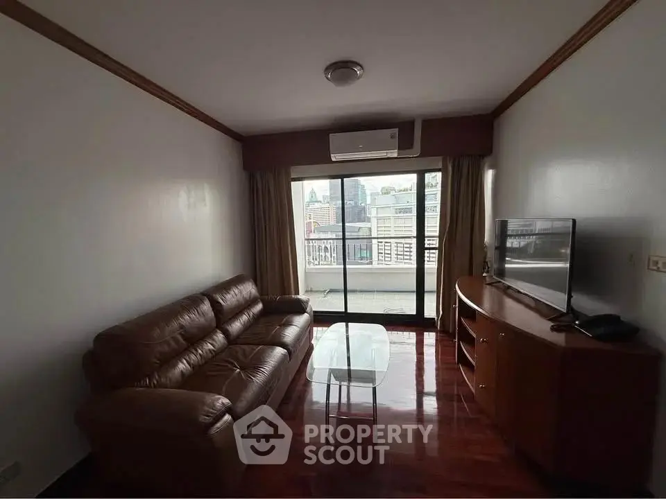 Cozy living room with leather sofa and city view balcony access.