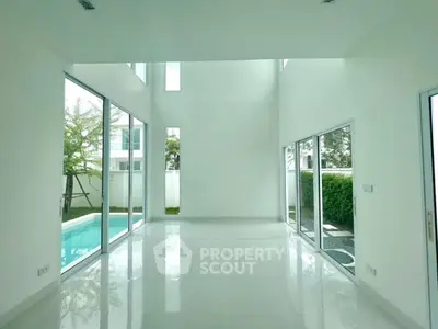 Spacious modern living room with high ceilings and pool view