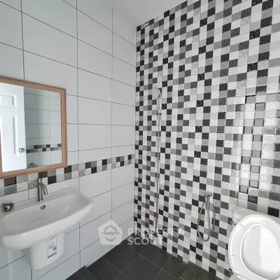 Modern bathroom with stylish black and white mosaic tiles and sleek fixtures.