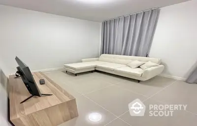 Spacious and modern living room with sleek white sectional sofa, large windows draped in elegant curtains, and glossy tiled flooring, perfect for urban living.