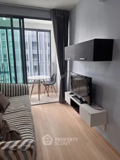 Modern living room with balcony access and stylish furniture in a high-rise apartment.