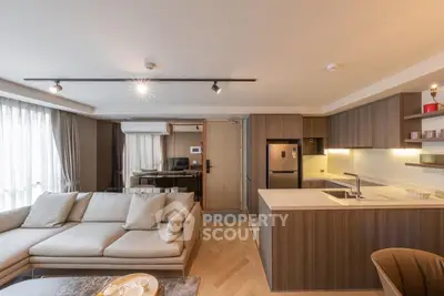 Modern open-layout living room and kitchen with sleek design and natural light.