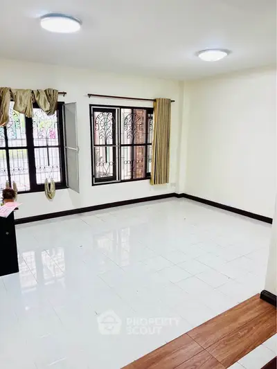 Spacious and bright living room with large windows and tiled flooring