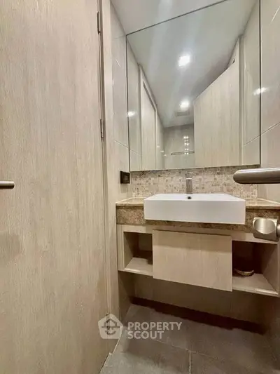 Modern bathroom with sleek sink and large mirror in stylish apartment.