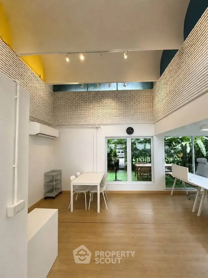 Spacious modern living room with high ceilings and garden view, perfect for family gatherings.