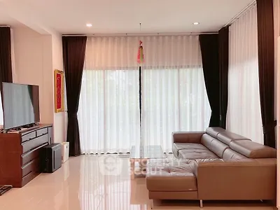 Spacious living room with modern leather sofa and large TV, perfect for relaxation.