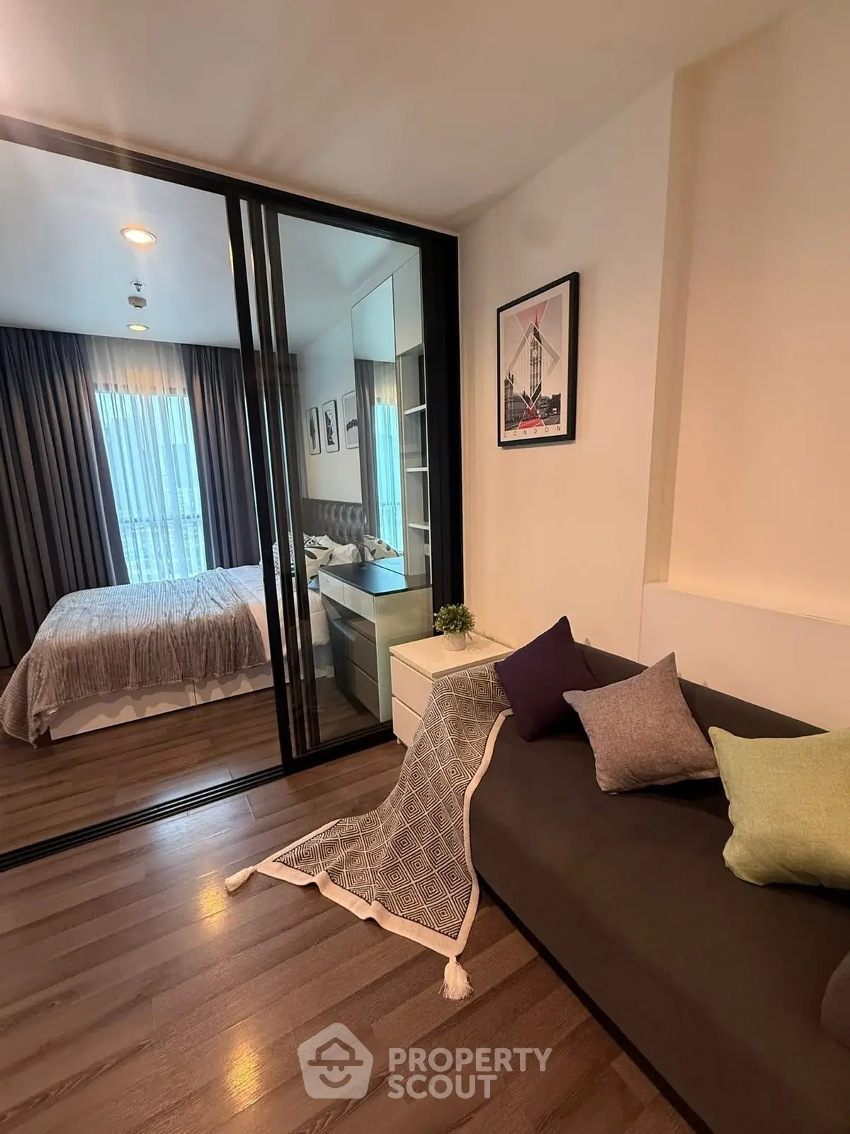 Modern apartment interior with cozy living room and stylish bedroom separated by glass doors.