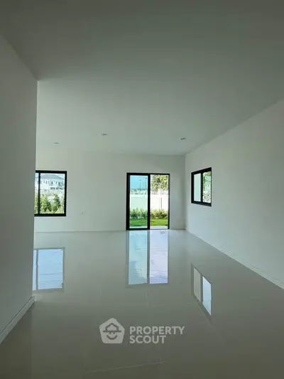Spacious empty living room with large windows and glossy tiled floor