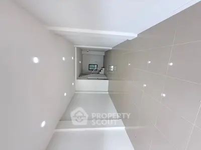 Spacious modern hallway with glossy tiled floors and recessed lighting.