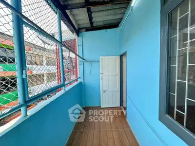 Charming small balcony with blue walls and tiled floor, perfect for cozy outdoor relaxation.