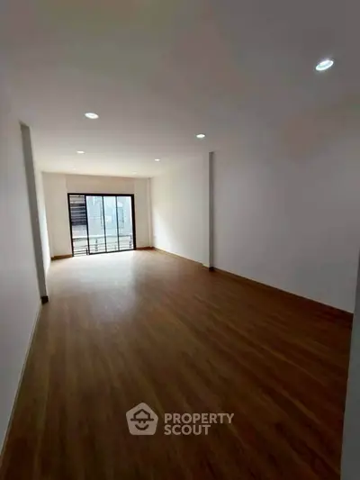 Spacious empty room with wooden flooring and large window