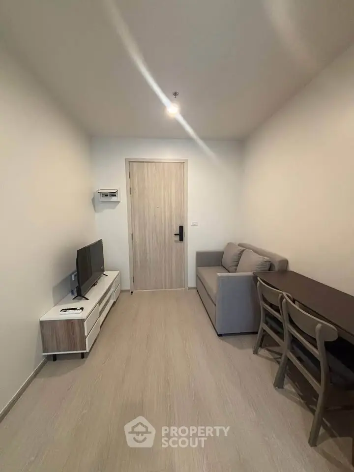 Modern living room with cozy sofa, TV unit, and dining table in compact apartment.