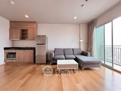 Modern living room with sleek kitchen and city view balcony in high-rise apartment.
