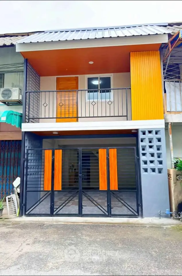 Modern two-story townhouse with vibrant orange accents and sleek black railings.