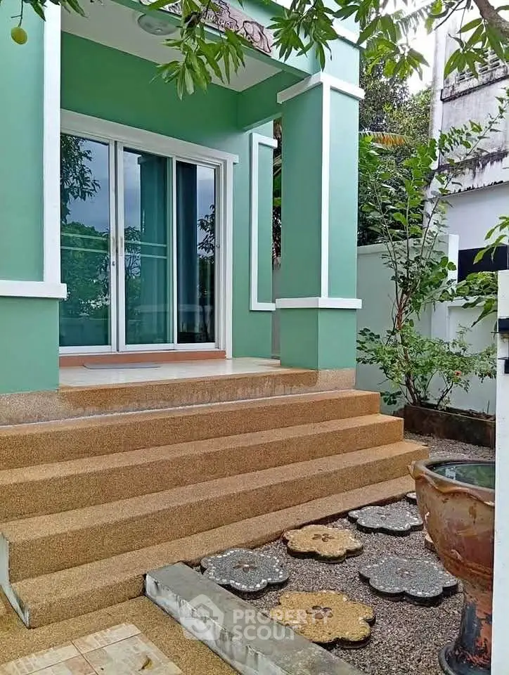 Charming green exterior with inviting entrance and decorative steps