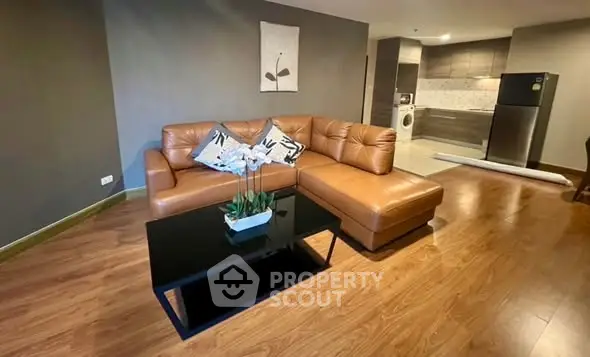 Spacious living room with modern leather sofa and open kitchen layout