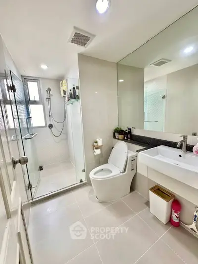 Modern bathroom with glass shower, sleek fixtures, and ample lighting