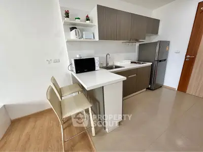 Modern kitchen with sleek cabinetry, stainless steel fridge, and breakfast bar in a stylish apartment.