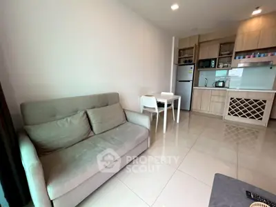Modern open-layout living room with kitchen, featuring sleek appliances and cozy seating area.