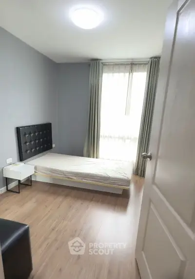 Cozy minimalist bedroom with natural light and wooden flooring