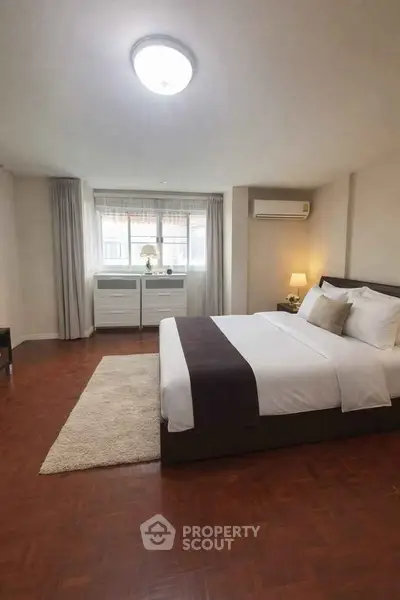 Spacious bedroom with modern decor and large window for natural light.