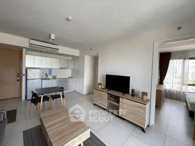 Modern open-plan living room with sleek kitchen and cozy dining area, featuring natural light and stylish furnishings.