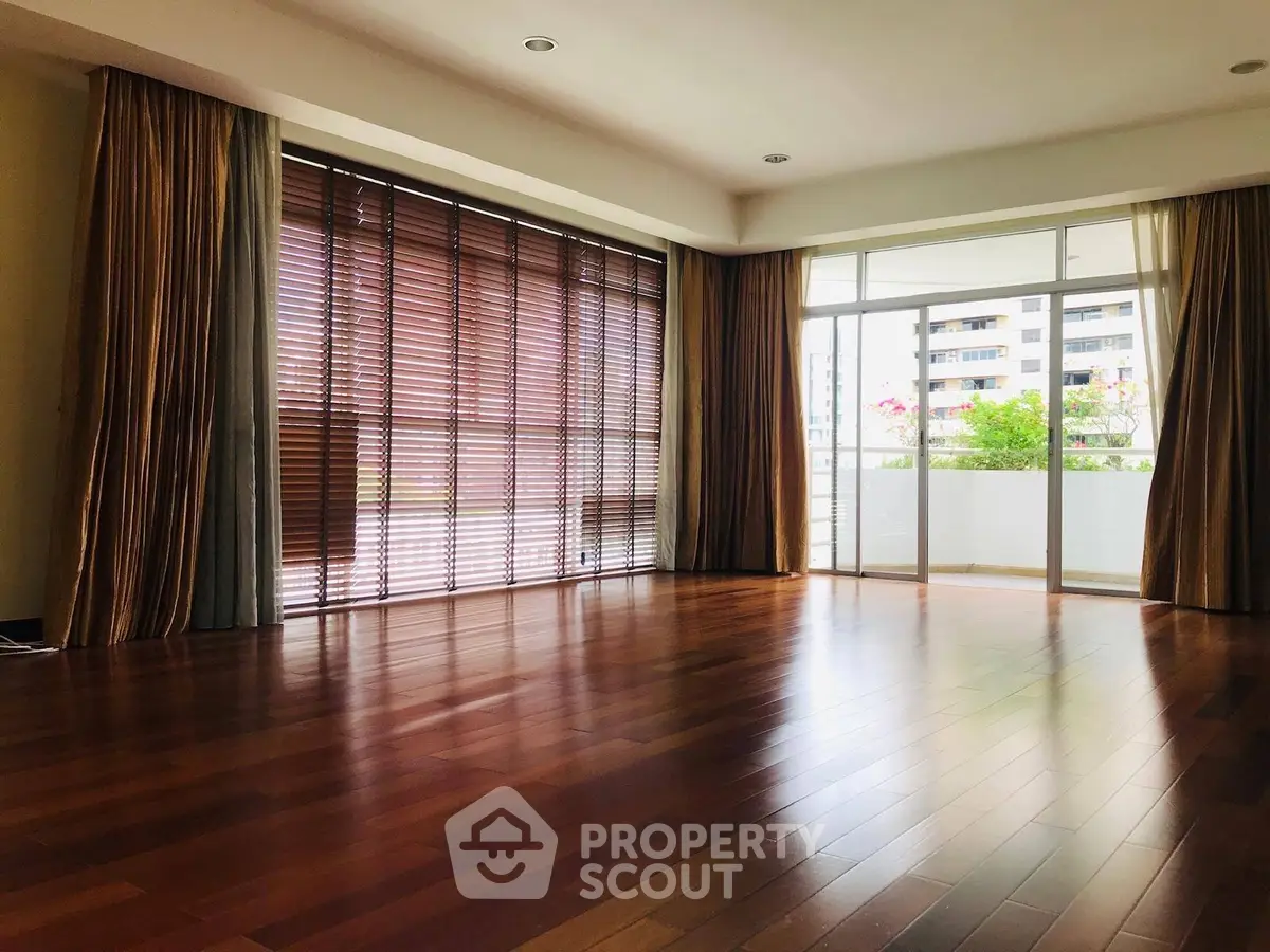 Spacious living room with wooden flooring and large windows in modern apartment